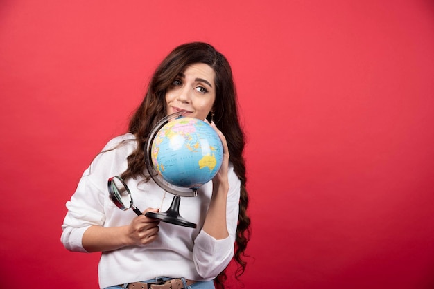 Happy woman posing with globe and magnifying glass. High quality photo