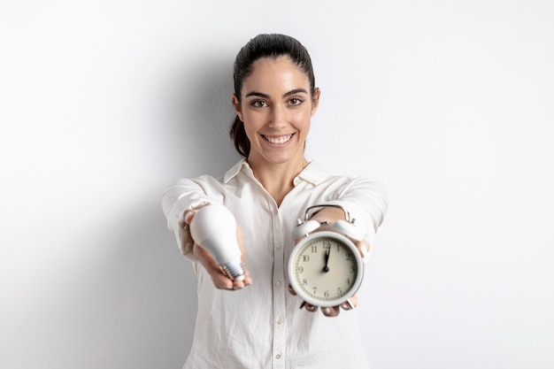 Happy woman posing with light bulb and clock