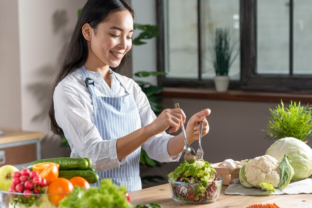 Счастливая женщина готовит здоровый салат на кухне