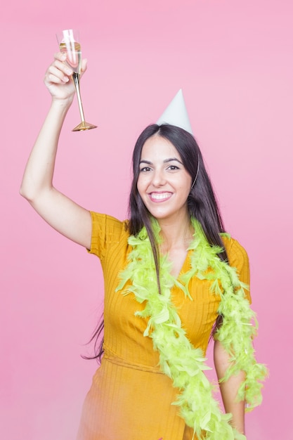 Happy woman raising champagne toast wearing boa and party hat