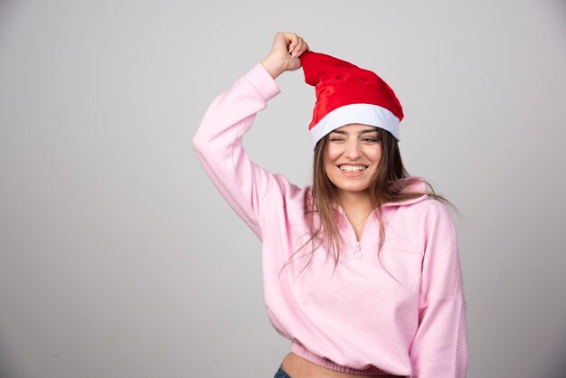 A happy woman in Santa Claus red hat posing .