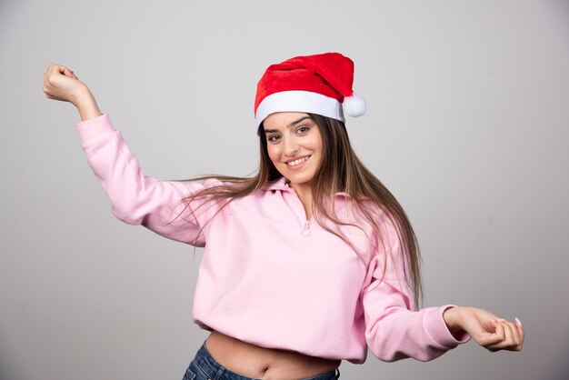 A happy woman in Santa Claus red hat posing .