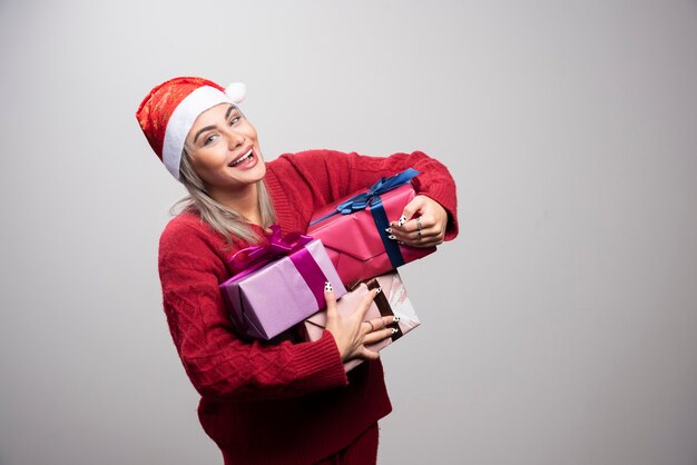 Foto gratuita donna felice in cappello della santa che tiene mazzo di scatole regalo.