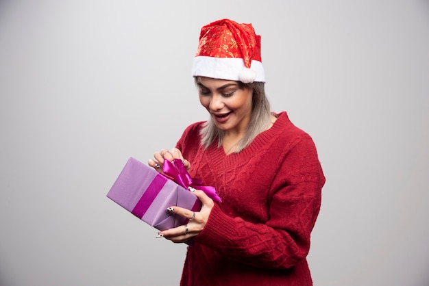 Happy woman in Santa hat looking at Christmas gift.