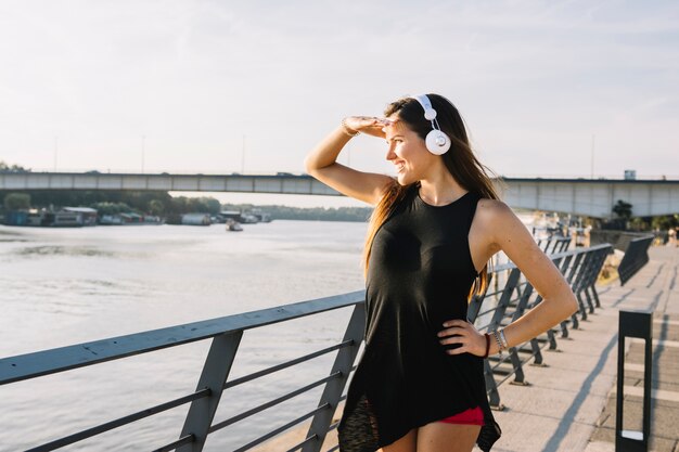 Happy woman shielding her eyes while looking at river