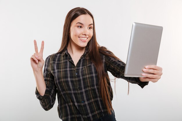 Happy Woman in shirt making selfie on tablet computer