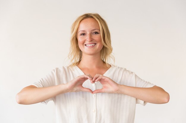 Happy woman showing hand heart gesture