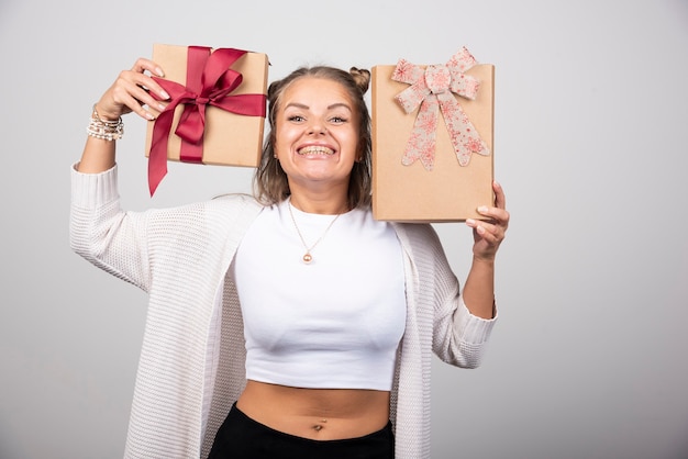 Free photo happy woman showing holiday gifts on gray wall.