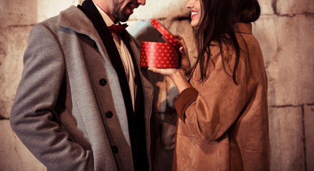 Happy woman showing present box to young man