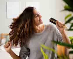 Foto gratuita donna felice che canta nella spazzola per capelli a casa