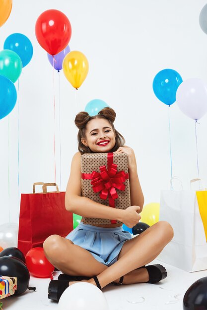 Happy woman sits in lotus position holding big gift box