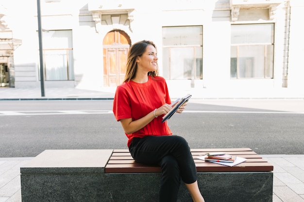 Happy woman sitting on bench with diary