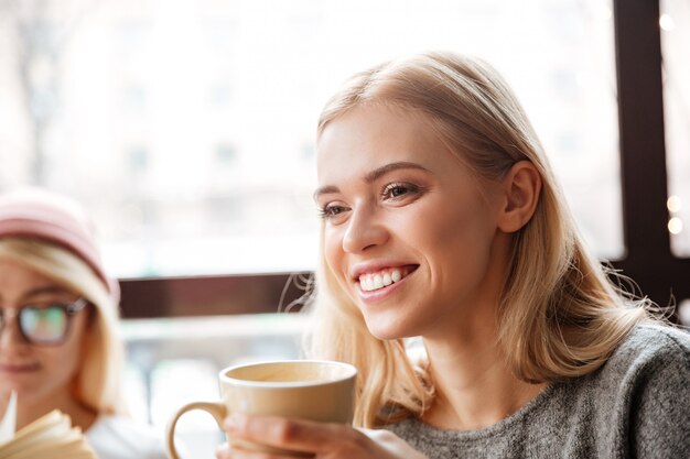 カフェに座って、コーヒーを飲みながら幸せな女。