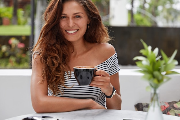 コーヒーショップに座っている幸せな女