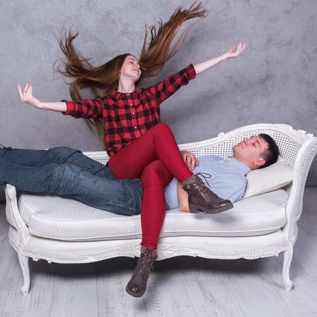 Happy woman sitting on man on sofa