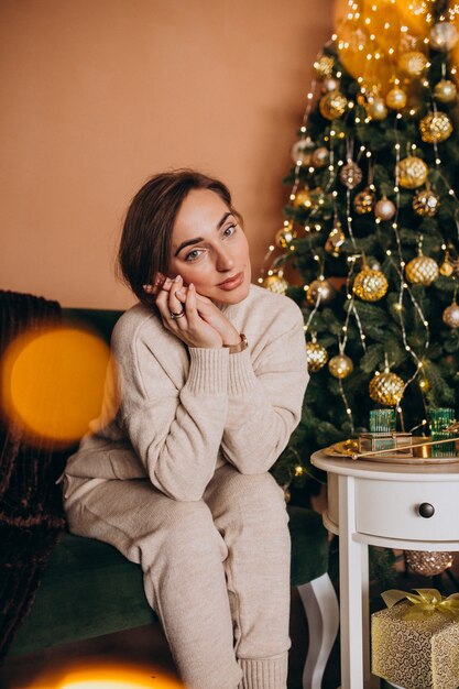 Happy woman sitting on sofa by the christmas tree