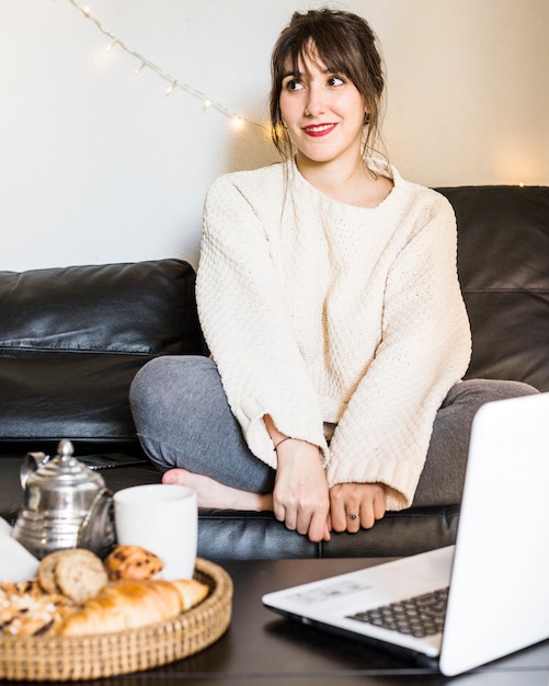 Happy woman sitting on sofa looking away