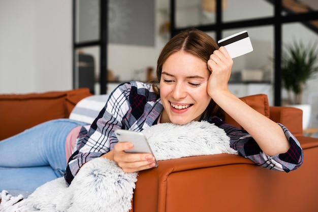 Happy woman sitting on sofa looking at phone