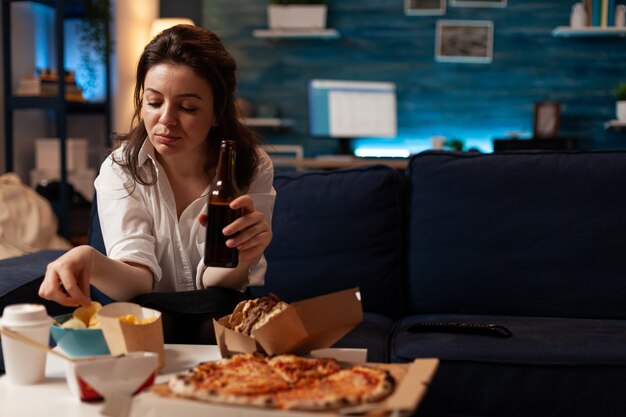 Happy woman sitting on sofa watching comedy movie film on television in evening