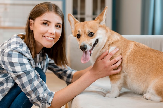 Счастливая женщина улыбается во время позирования со своей собакой