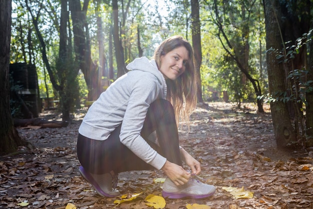 Free photo happy woman in sportswear tying shoelaces