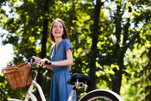 Счастливая женщина, стоящая рядом с велосипедом