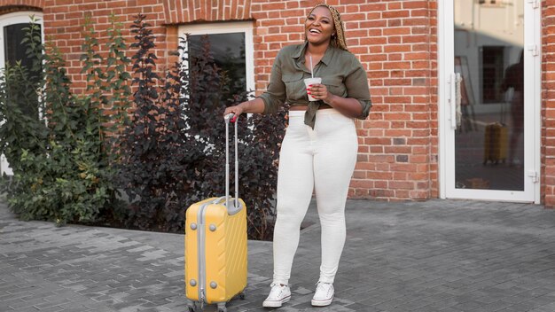 happy woman standing next to her yellow luggage