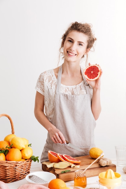 Happy woman standing indoors near table with a lot of citruses