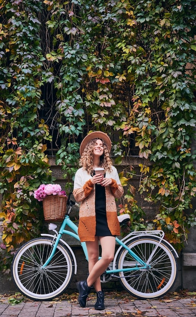 Happy woman standing near vintage bicycle in city park