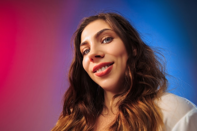 The happy woman standing and smiling against colored.