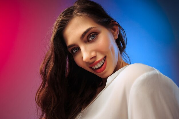 Happy woman standing, smiling on colored studio background. Beautiful female half-length portrait. Young satisfy woman. Human emotions, facial expression concept.