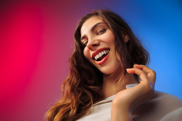 Happy woman standing, smiling on colored studio.