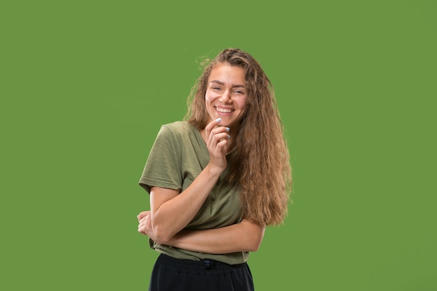 Happy woman standing and smiling isolated on green studio background. Beautiful female half-length portrait. Young emotional woman.