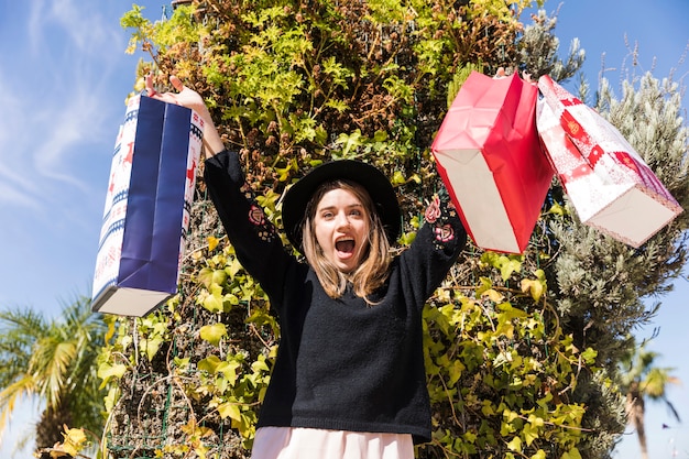 Free photo happy woman standing on street with shopping bags