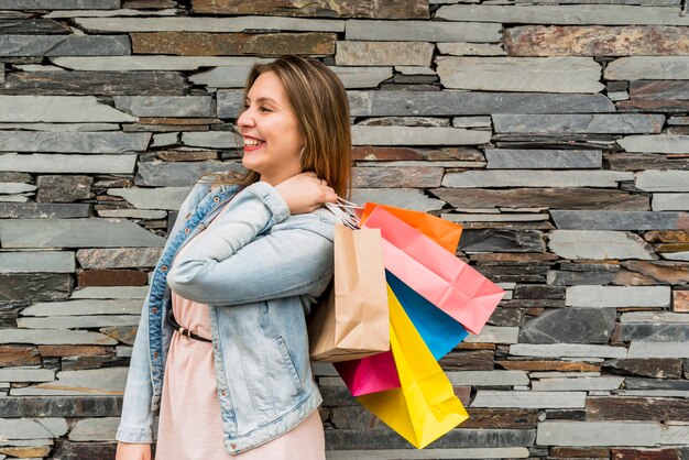 Happy woman standing with colourful shopping bags