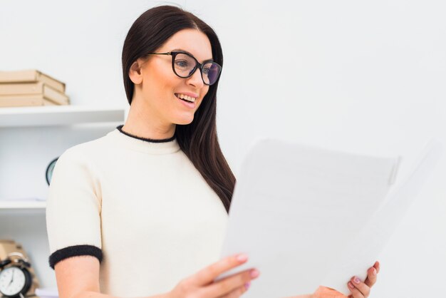 Happy woman standing with papers in office