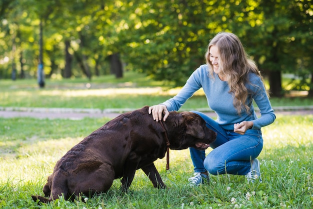 庭で彼女の犬を撫でている幸せな女性