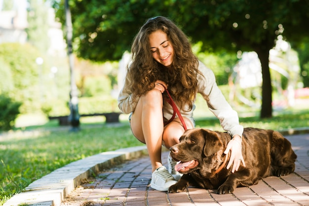 Foto gratuita donna felice che segna il suo cane nel parco