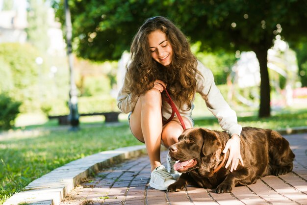 Happy woman stroking her dog in park