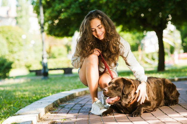 公園で彼女の犬を撫でている幸せな女性