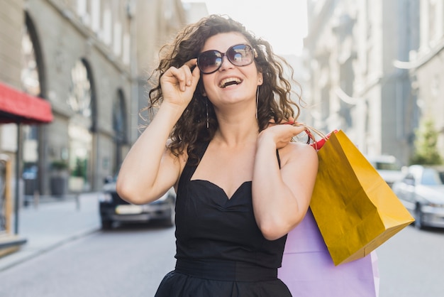 ショッピングバッグを持つサングラスの幸せな女性
