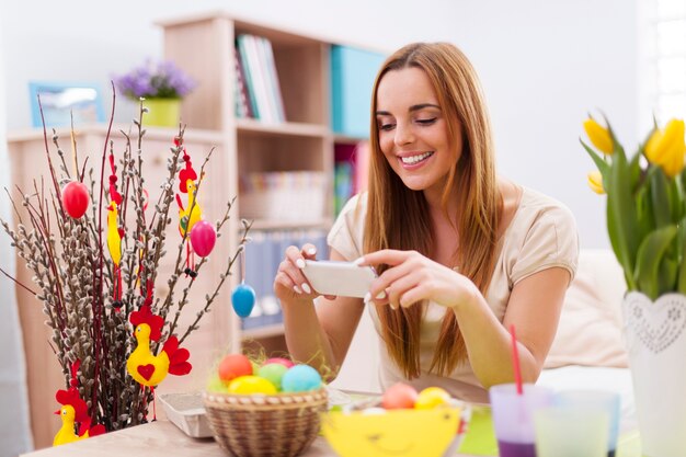 Happy woman taking photo by mobile phone in easter holiday