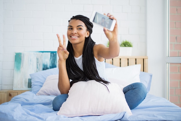 Happy woman taking selfie showing horns gesture