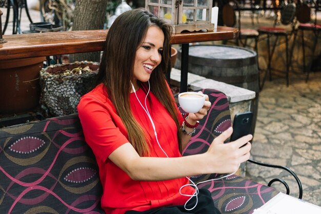 Happy woman taking selfie while drinking cup of coffee