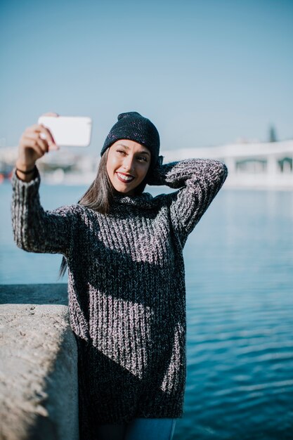 Happy woman taking selfie with water in background