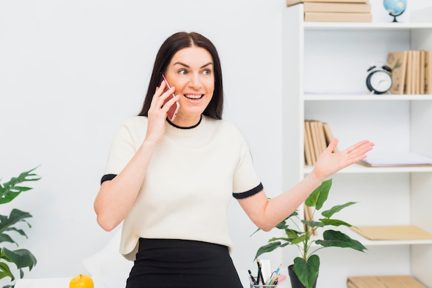 Happy woman talking by phone in office