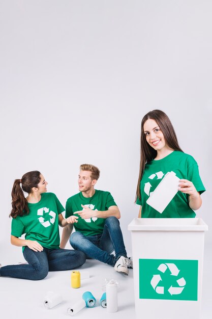 Happy woman throwing bottle in dustbin with recycle icon