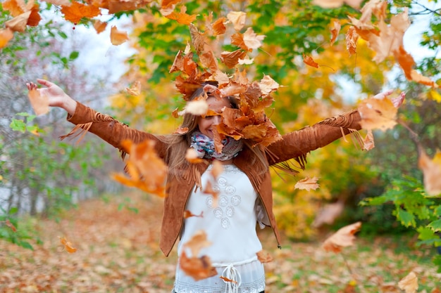 Free photo happy woman throws autumn leaves