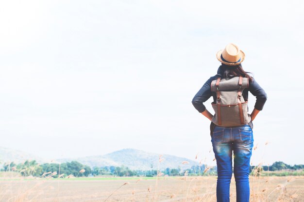 Happy woman traveler looking to blue sky with mountain background, wanderlust travel concept, space for text