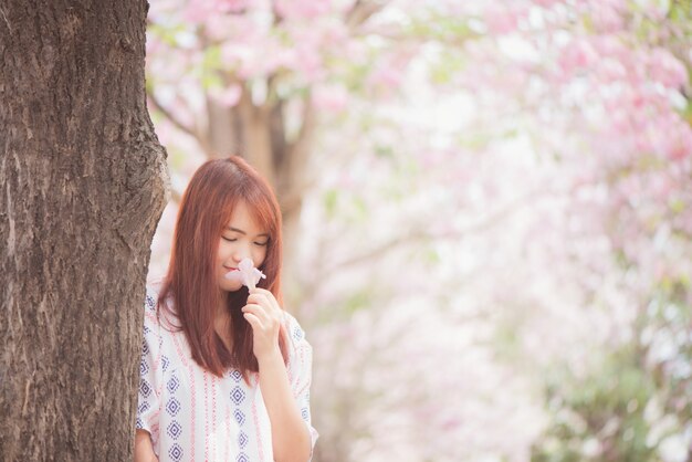 행복한 여자 여행자는 휴가에 벚꽃이나 사쿠라 꽃 나무와 함께 무료로 휴식을 취